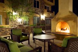 Exteror image of Andalucia Senior Apartments lounge area with dark brown wicker chairs with green cushions and fireplace