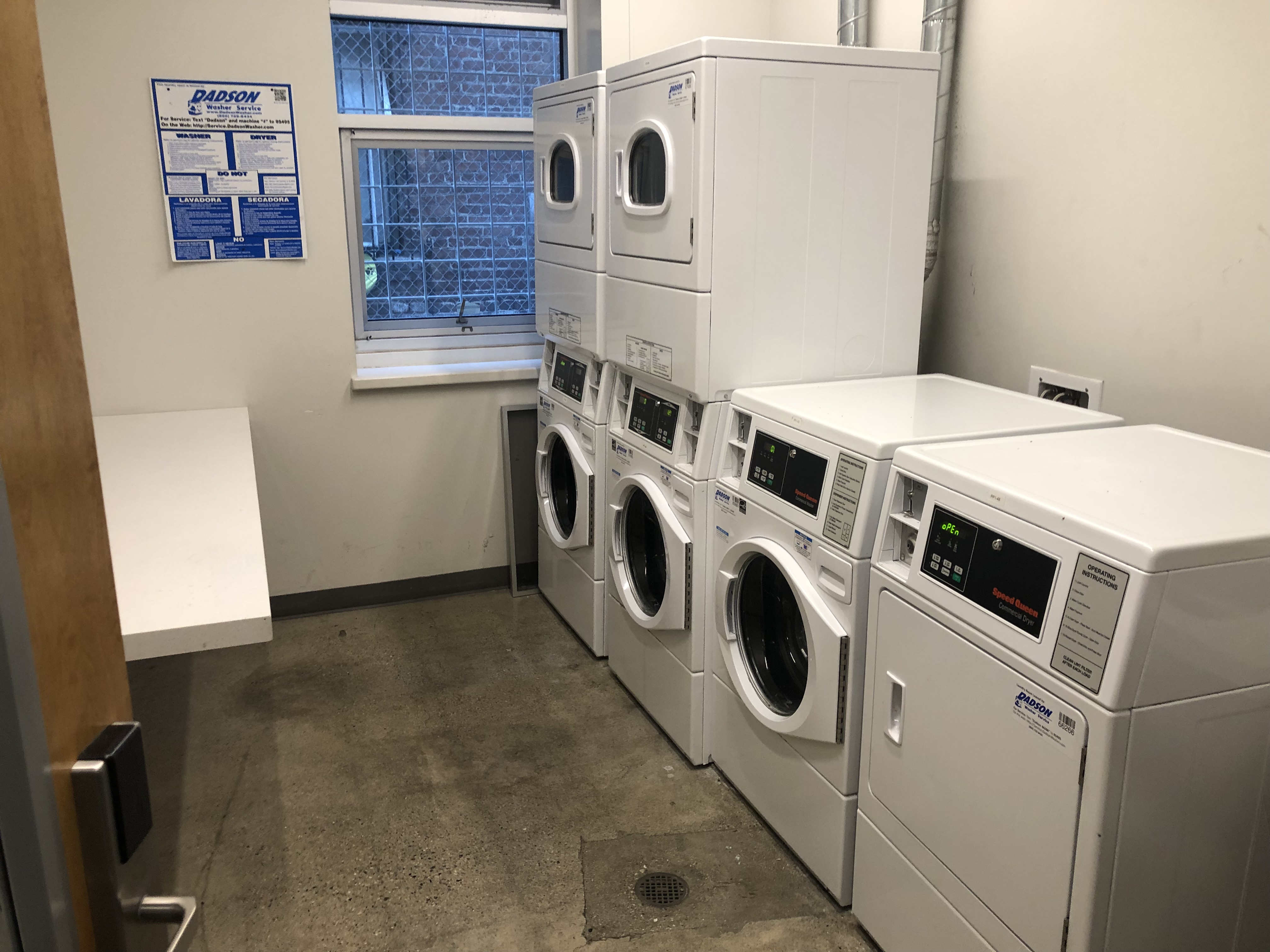 Interior view of a laundry room at Simone Hotel, three washers and three dryers.