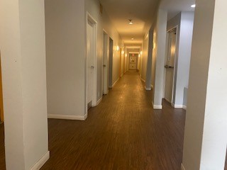 View of a hallway that leads to units. It has wooden flooring,