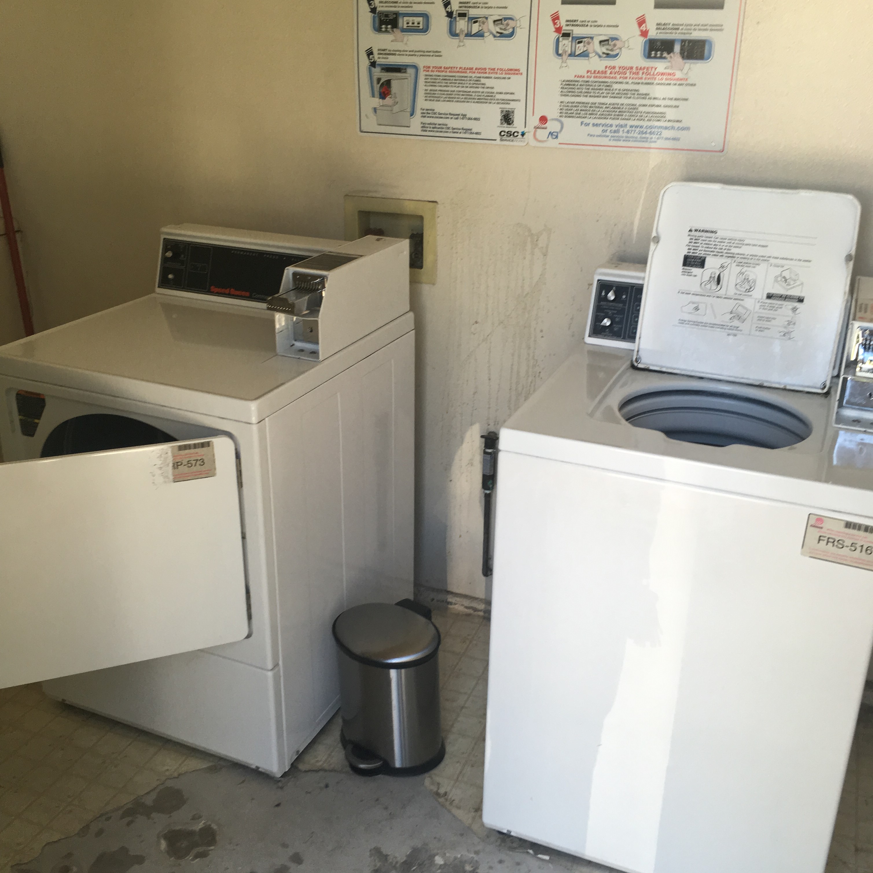Small laundry room with one washer and one dryer. Intructions on how to use machinery are posted on the wall. There is a small trash bin in betweeen the machines.