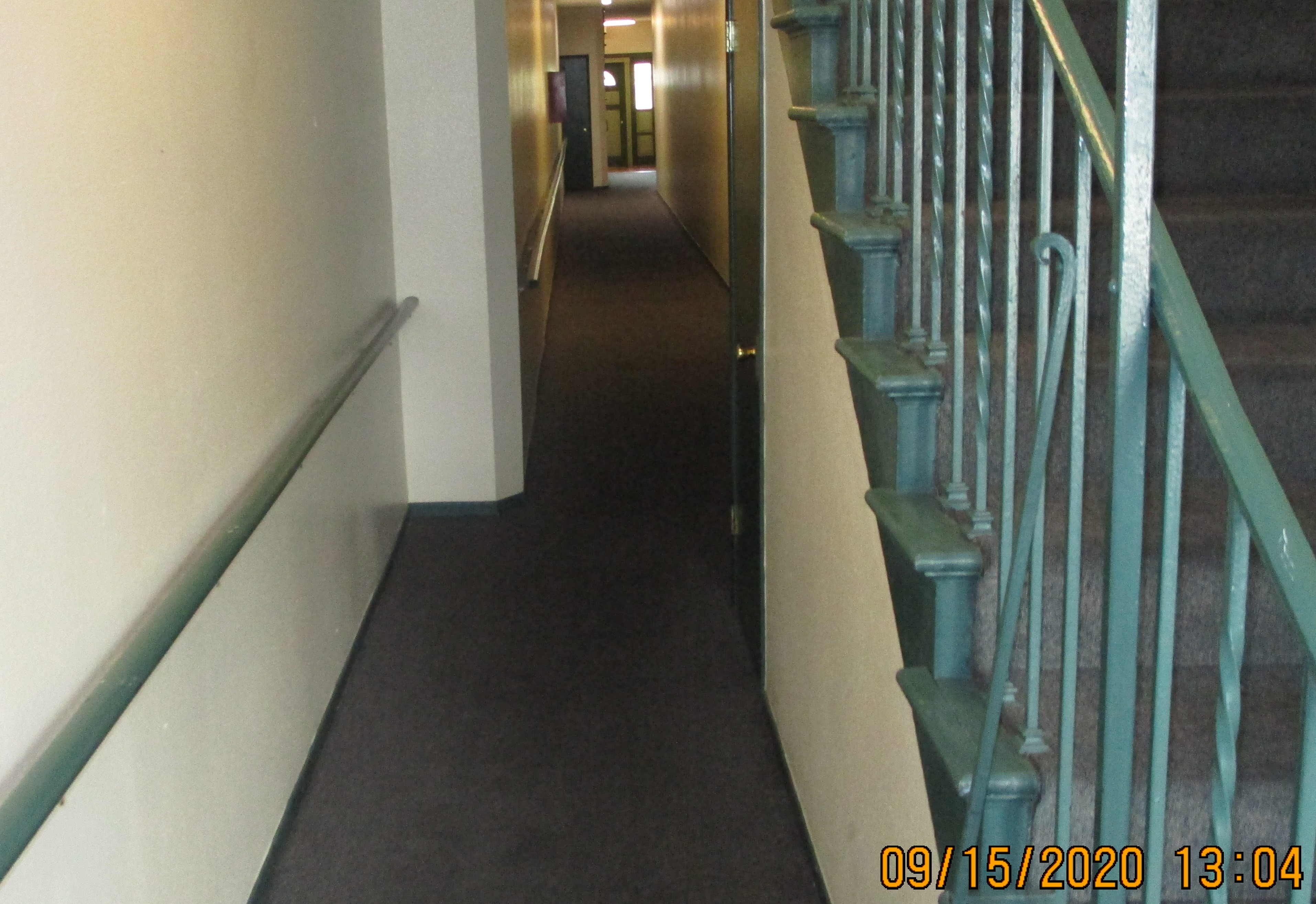 Image of an interior hallway with stairs leading to an upper level on the right hand side.