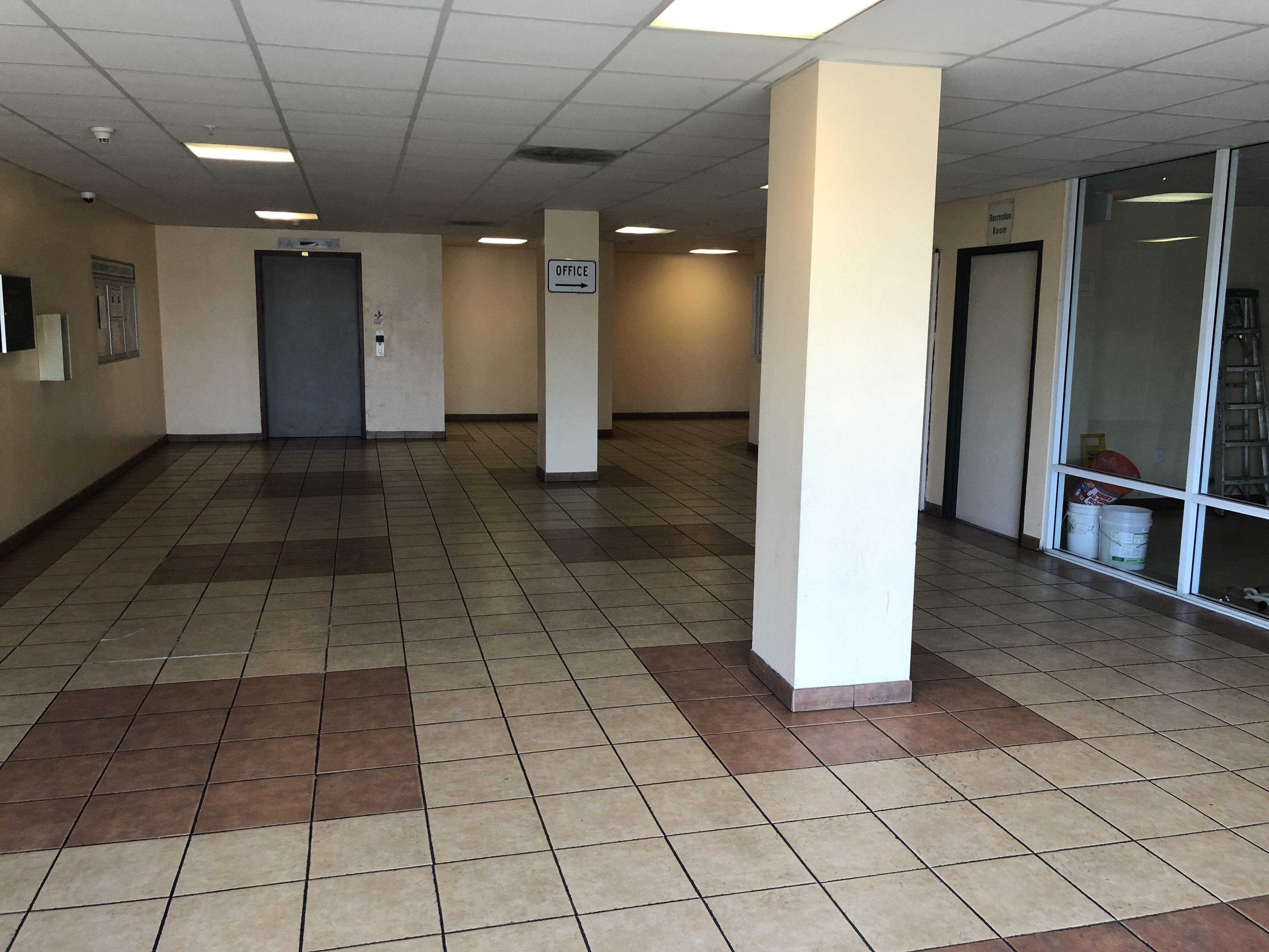 vermont city lights lobby area. large tiled area with bulletin board on wall. access to office area