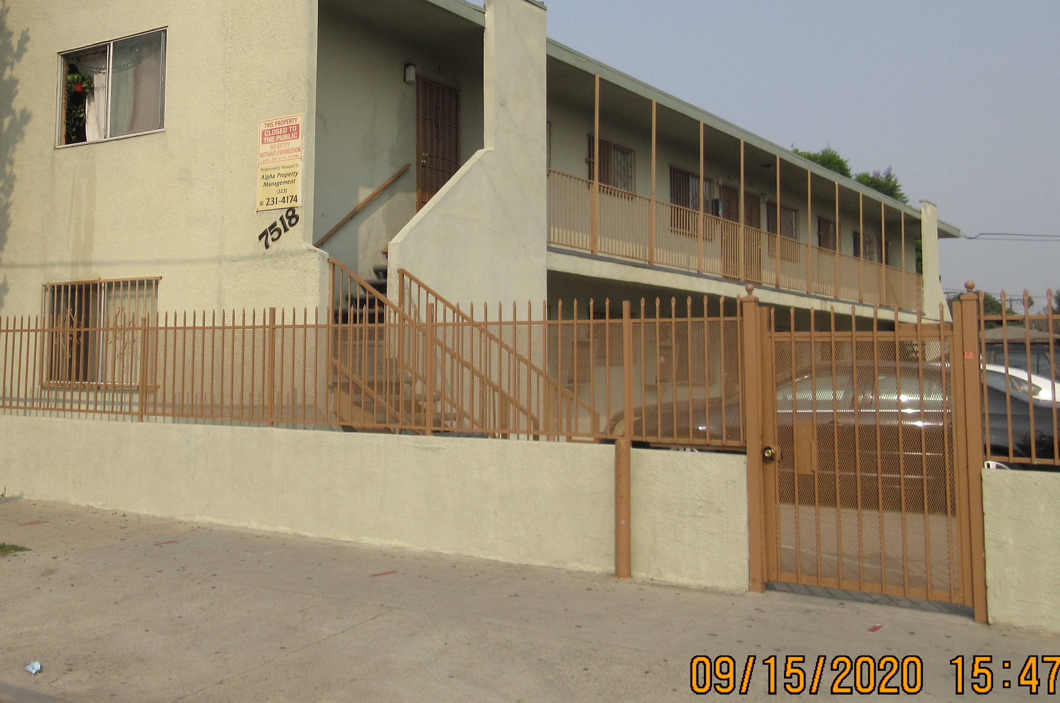 View of a two story building, gated, building number, stairway with handrails.