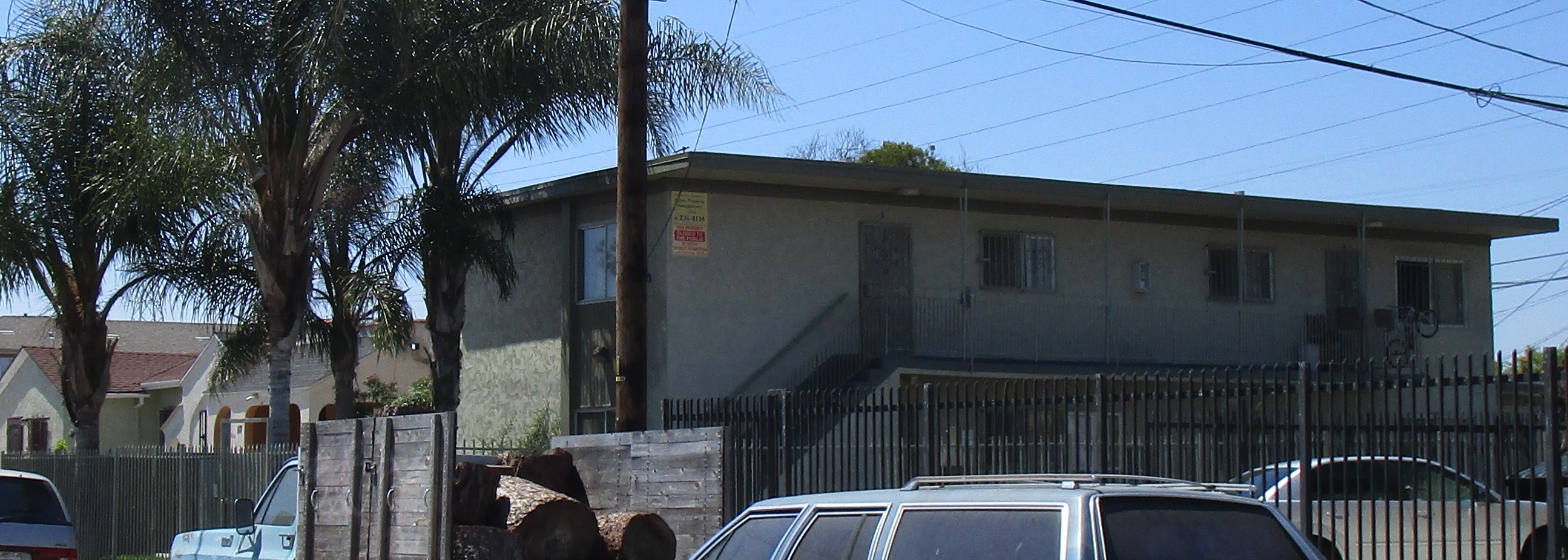 Street view of property showing a two story gated building with palm trees along the front