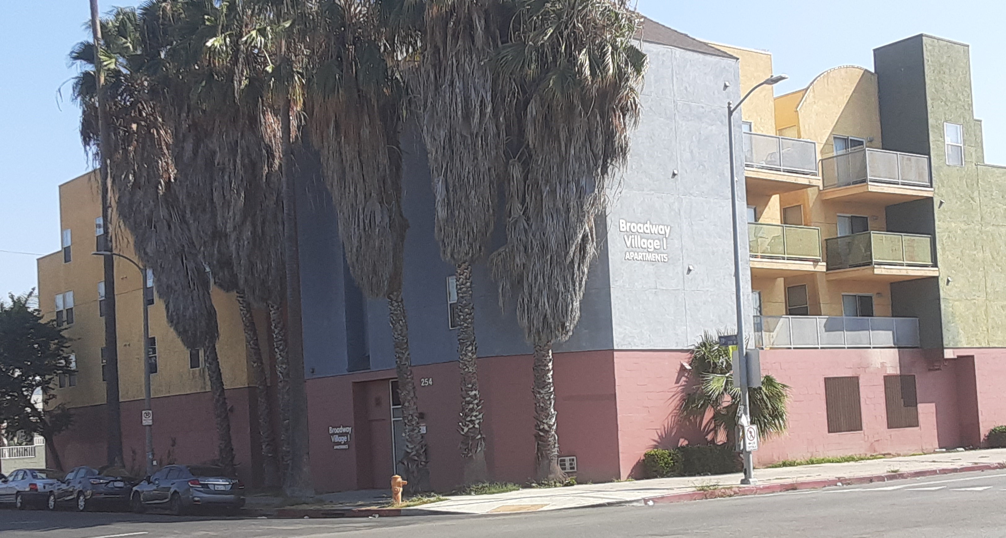 Corner street view of four story building. Some units have balcony access