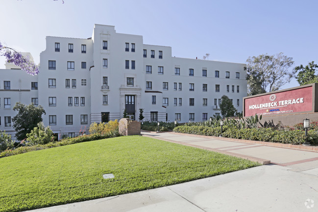 Linda Vista Apartments- Front of Building. Multi level white building. Large front lawn that has well maintained grass and various plants. Walkway leading up to front of building.