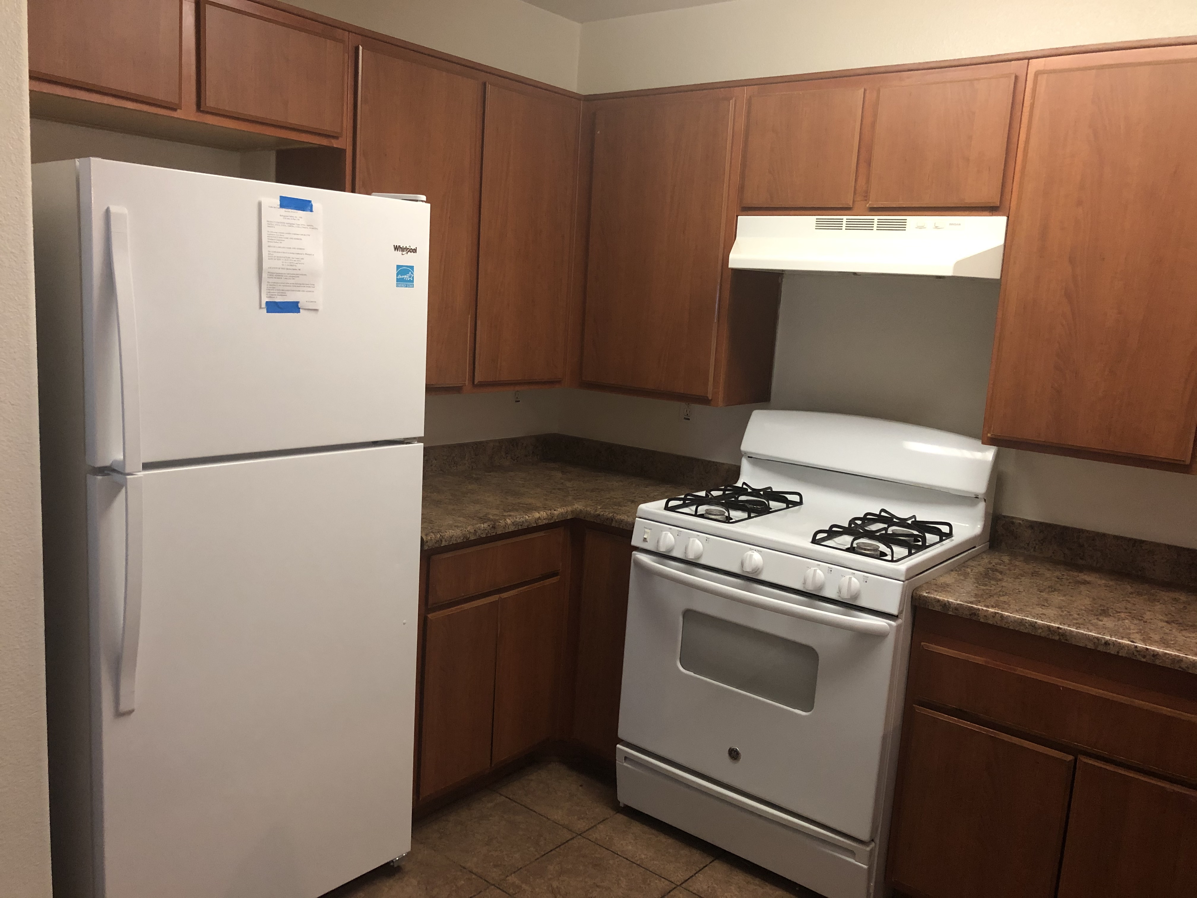 Interior view of a kitchen in a unit at Casa de Angles, showing a refrigerator, stove, counters and cabinets